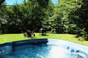 a hot tub in a yard with a bench at Chalets Alpins - 16 Chemin des Skieurs in Stoneham