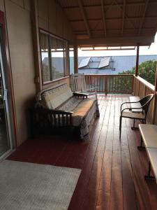 eine Veranda mit einer Bank und Stühlen auf einer Terrasse in der Unterkunft Ohana Hale in Kailua-Kona