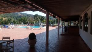 eine Terrasse mit Topfpflanze und Pool in der Unterkunft Apartamento Hotel Cavalinho Branco in Águas de Lindóia