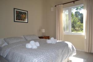 Un dormitorio con una cama con almohadas blancas y una ventana en Casitas La Invernada en Villa Giardino