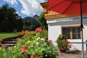 a building with a red umbrella and some flowers at Haus Frainer in Wald am Arlberg