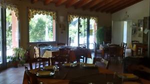 un comedor con mesas, sillas y ventanas en B&B IL BOSCHETTO, en Calestano