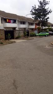 ein Parkplatz mit einem grünen Auto vor einem Gebäude in der Unterkunft Juddy Place in Nairobi