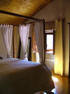 a bedroom with a bed with curtains and a window at Bairro do Casal - Turismo d'Aldeia in Vila Nova de Foz Coa