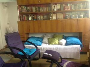 Morne-à-lʼEauにあるVilla Les Violettesのベッド1台、椅子、本棚が備わる客室です。