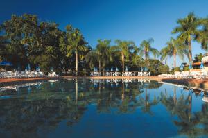 a large pool of water with palm trees and chairs at Resort Fazenda Sao João in São Pedro