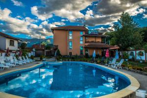 a pool at a hotel with chairs and a building at Complex Balkandzhii in Apriltsi