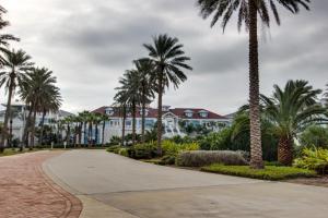 een loopbrug met palmbomen voor een gebouw bij Point West Resort in Galveston