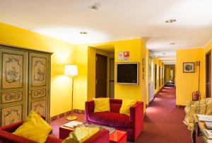 sala de estar con paredes amarillas y sofá rojo en Hotel Alpi Resort, en Turín