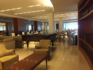 a restaurant with a piano and tables and chairs at NH Gran Hotel Provincial in Mar del Plata