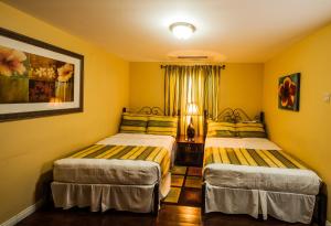 two beds in a room with yellow walls at Inn at 87 in Port-of-Spain