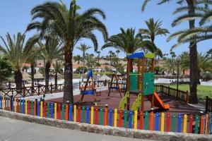 un parco giochi con scivolo in un parco con palme di Bungalow Luisy a Maspalomas