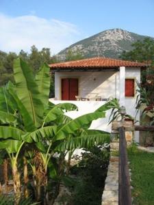 a small white house with a mountain in the background at Hotel Heleni Apartments in Ancient Epidavros