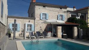 a pool with chairs and an umbrella next to a building at Holiday Home Peruski in Peruški