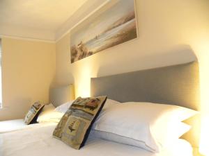 a bedroom with a white bed with a painting on the wall at Durlston House in Lymington