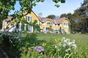 a large yellow house with a yard with flowers at Auberge sur la Côte in La Malbaie