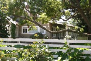 una casa blanca con una valla y un árbol en Cottage on Armstrong, en Lodi