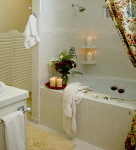 Cottage on Armstrong في لودي: حمام مع حوض استحمام مع الشموع وكأسين من النبيذ