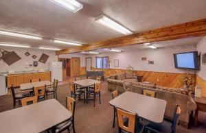 Habitación grande con mesas, sillas y TV. en City Center Motel, en West Yellowstone
