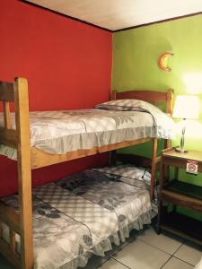 two bunk beds in a room with a red wall at Hotel & Hostel Sloth Backpackers in Monteverde Costa Rica