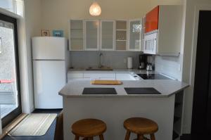 eine Küche mit einem weißen Kühlschrank und 2 Hockern in der Unterkunft Meadowbrook Guest Suite in Brentwood Bay