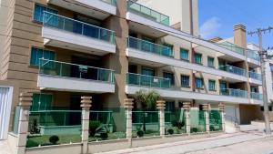 un edificio de apartamentos con balcones verdes y una palmera en Don Rafael 02 dormitórios, 80m mar, Mariscal, en Bombinhas