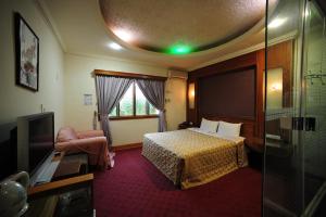a hotel room with a bed and a tv at Golden Motel in Hsinchu City