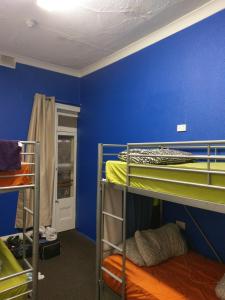 
a bunk bed in a small room with a blue wall at Adelaide Travellers Inn Backpackers Hostel in Adelaide
