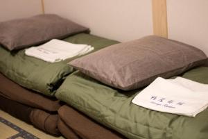 two beds sitting next to each other in a room at Kamoya Ryokan in Kyoto