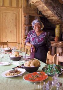 una mujer parada frente a una mesa con comida en Hospedaje y Agrocamping Relmucura, en Melipeuco