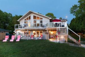 una casa grande con sillas rosas en el césped en N' This on the Bay -Lower Level Vacation Suite, en Wiarton