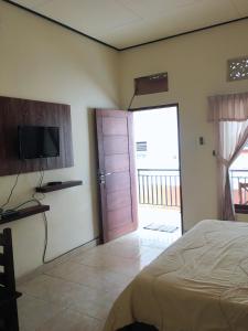 a bedroom with a bed and a tv and a door at DSTAY Kost Bali in Jimbaran