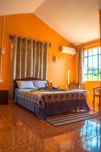 a bedroom with a bed with orange walls at Merlin Guest House in Rodrigues Island