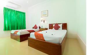 two beds in a room with green curtains at Blossoming Romduol Boutique in Siem Reap