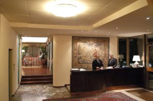 Hotel Torretta في مونتيكاتيني تيرمي: رجلان يقفان عند مكتب في بهو الفندق