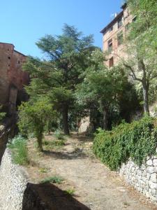 uma estrada de terra com árvores e uma parede de pedra em Hotel Mesón del Gallo em Albarracín