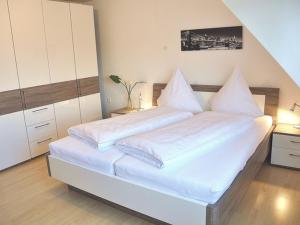 Cette chambre comprend un grand lit blanc avec des draps blancs. dans l'établissement Ferienhaus Jäger, à Friedrichshafen