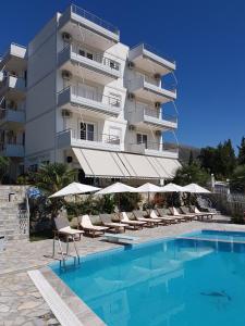 a hotel with a swimming pool and chairs and a building at Perivolos Apartments in Dhërmi