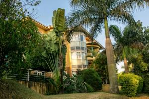 a yellow house with palm trees in front of it at Enkombe Place in Kampala