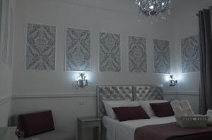 a bedroom with two beds and a chair and a chandelier at Ca dei Nobili in Genoa