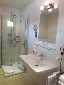 ein Bad mit einem Waschbecken und einer Dusche mit einem Spiegel in der Unterkunft Gasthof-Pension Silvia in Haibach ob der Donau