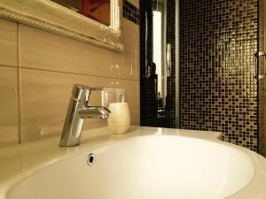 un lavandino del bagno con un rubinetto e uno specchio di Provance Apartment a Liepāja