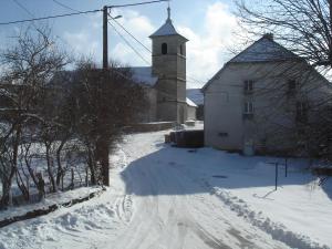 eine verschneite Straße, die zu einer Kirche mit einem Turm führt in der Unterkunft gite Loca in Provenchère