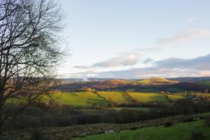 a view of a green field with trees and hills at Owl Barn at Penygaer Great views of Brecon Beacons in Llandovery