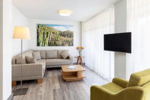a living room with a couch and a flat screen tv at Apartamentos Tigaiga Suites in Puerto de la Cruz