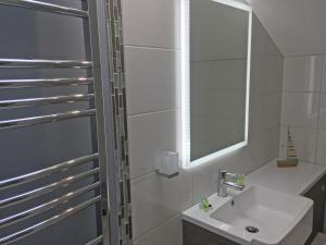 Baño blanco con lavabo y espejo en The Waterfront Inn en Westward Ho