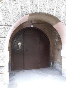 a dark brown door in a brick wall with an arch at Apartment on Gatchinskaya in Saint Petersburg