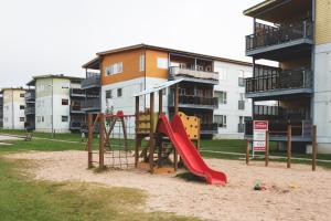 a playground with a slide in the sand in front of a building at Jaamamõisa apartement in Tartu