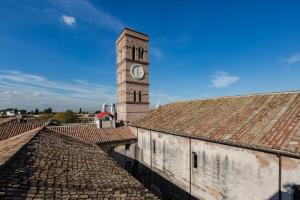 a clock tower on top of a building with roofs at Domus Sessoriana in Rome +137 photos
