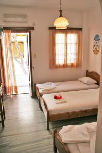 a bedroom with three beds and a window and a door at Pension Piertzovani in Parikia